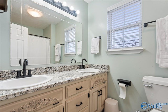 bathroom featuring double vanity, toilet, and a sink