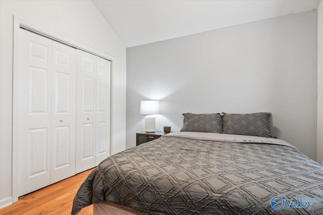 bedroom with a closet, lofted ceiling, and light wood-type flooring