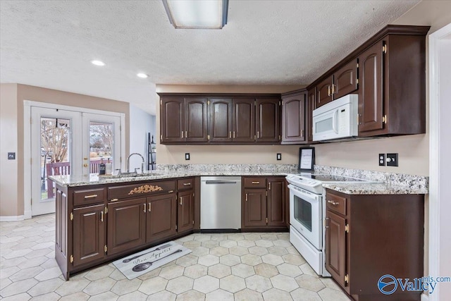 kitchen featuring a sink, dark brown cabinets, a peninsula, and white appliances