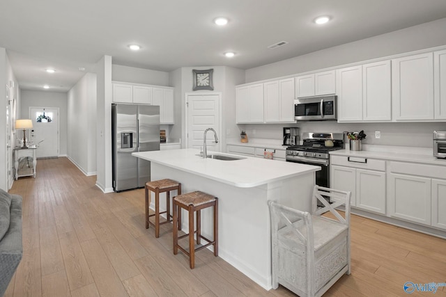 302 Shangrila Way, Meridianville, AL 35759 - kitchen featuring stainless steel appliances, a sink, a breakfast bar, light wood finished floors, and white cabinets
