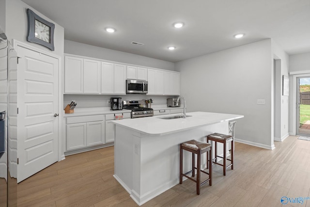 302 Shangrila Way, Meridianville, AL 35759 - kitchen featuring appliances with stainless steel finishes, a sink, light wood-type flooring, a breakfast bar area, and white cabinets