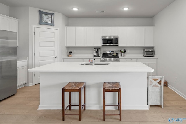 302 Shangrila Way, Meridianville, AL 35759 - kitchen featuring stainless steel appliances, light wood-style floors, a breakfast bar, a sink, and a kitchen island with sink