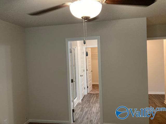 spare room featuring baseboards, wood finished floors, and ceiling fan