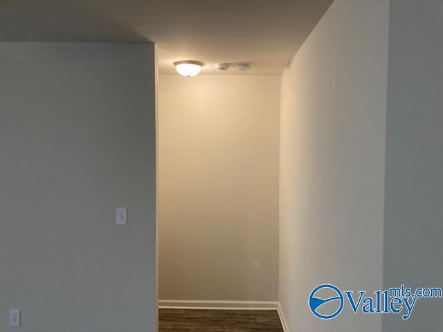 hallway with baseboards and dark wood-type flooring