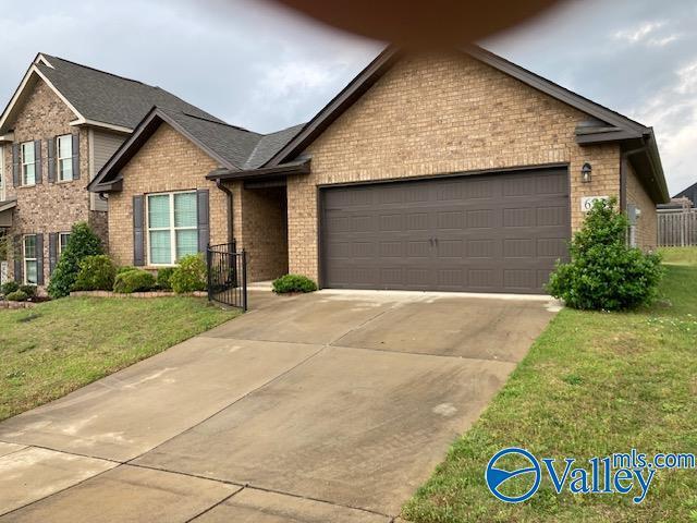 view of front of property with brick siding, a front lawn, driveway, and an attached garage