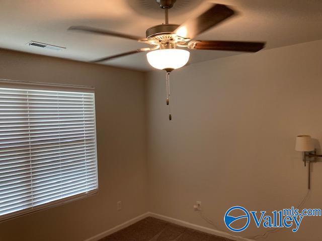 carpeted empty room featuring baseboards, visible vents, and ceiling fan