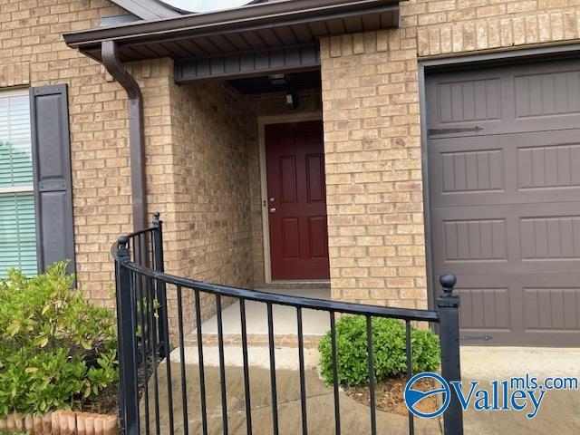 entrance to property with a garage and brick siding