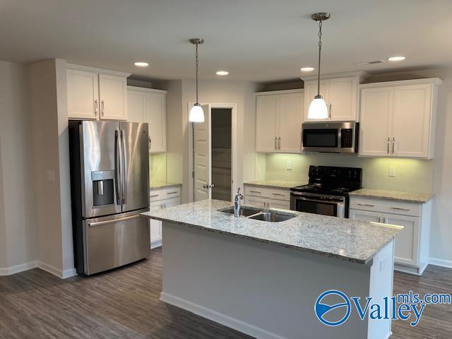 kitchen featuring white cabinetry, appliances with stainless steel finishes, backsplash, a sink, and baseboards