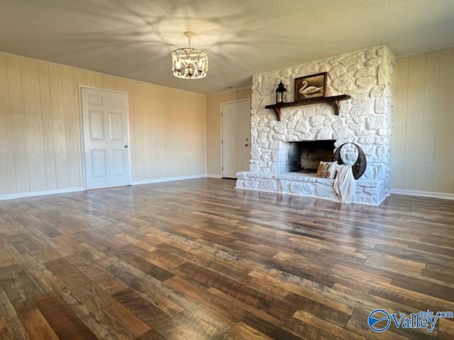 unfurnished living room with a chandelier, a fireplace, a textured ceiling, and dark hardwood / wood-style flooring