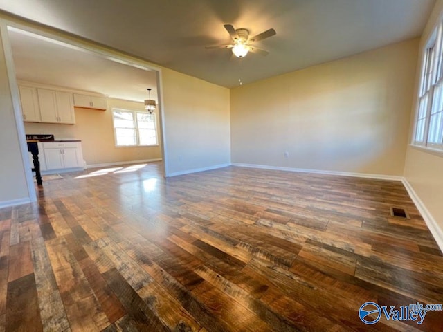 unfurnished living room with ceiling fan and dark hardwood / wood-style flooring