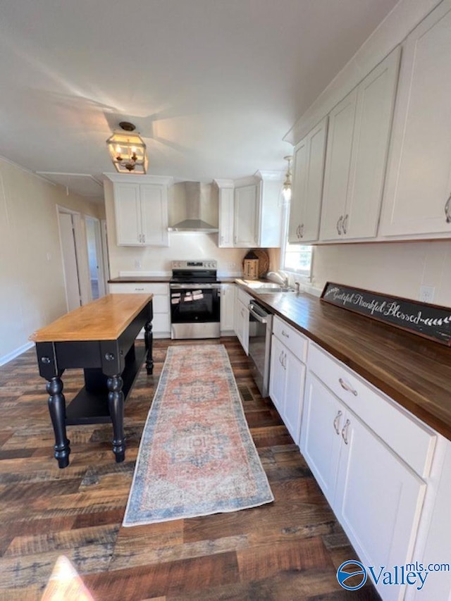 kitchen featuring white cabinetry, dark hardwood / wood-style floors, butcher block counters, wall chimney exhaust hood, and stainless steel appliances