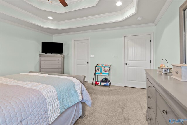 bedroom with a tray ceiling, ceiling fan, light colored carpet, and ornamental molding