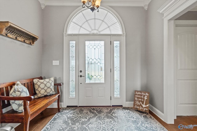 foyer featuring ornamental molding, an inviting chandelier, a healthy amount of sunlight, and wood-type flooring