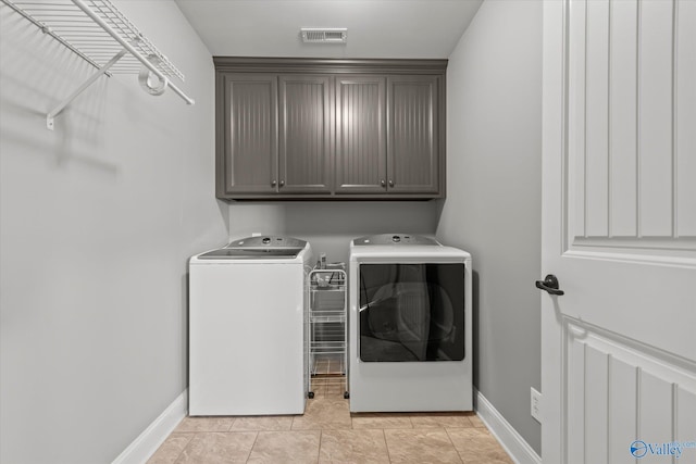 laundry room featuring cabinets, independent washer and dryer, and light tile patterned floors