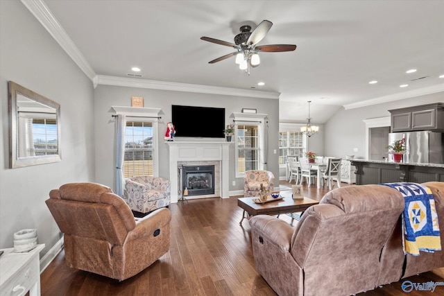 living room with a fireplace, dark wood-type flooring, ceiling fan with notable chandelier, and ornamental molding