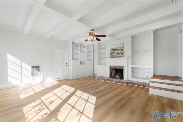 unfurnished living room featuring built in shelves, beam ceiling, a ceiling fan, a brick fireplace, and wood finished floors