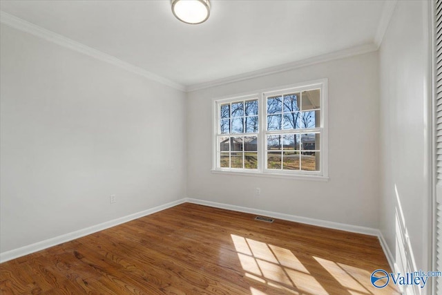 spare room featuring visible vents, baseboards, wood finished floors, and ornamental molding