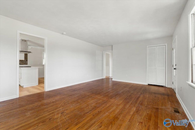 empty room featuring visible vents, baseboards, and wood finished floors