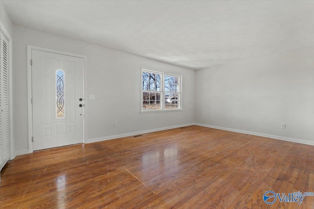 foyer entrance with wood finished floors, visible vents, and baseboards