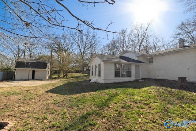 view of home's exterior featuring driveway, an outdoor structure, and a yard