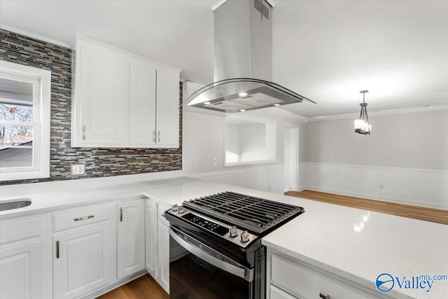 kitchen featuring stainless steel gas range, white cabinets, crown molding, and island range hood