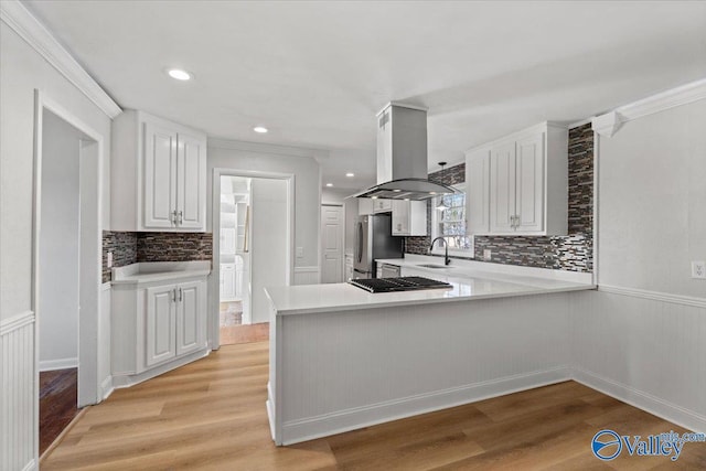 kitchen featuring island exhaust hood, light countertops, light wood-style floors, freestanding refrigerator, and a sink