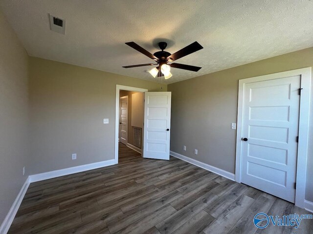 100 James Bowie Dr, Athens, AL 35611 - unfurnished bedroom featuring dark wood-type flooring, baseboards, a textured ceiling, and a ceiling fan