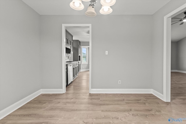 unfurnished dining area featuring ceiling fan with notable chandelier and light wood-type flooring