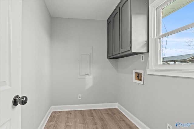 clothes washing area with washer hookup, light hardwood / wood-style floors, and cabinets