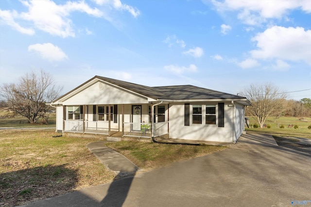 view of front facade featuring a front lawn, covered porch, and driveway