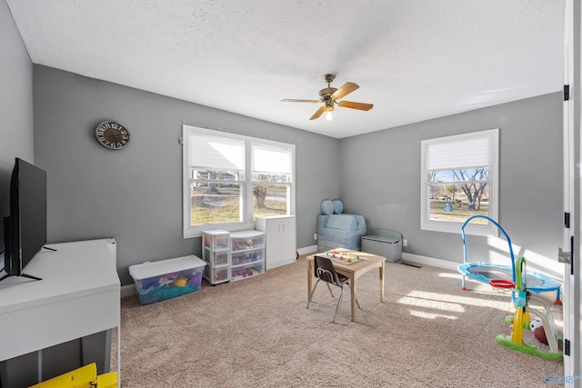 game room featuring baseboards, a ceiling fan, carpet flooring, and a textured ceiling