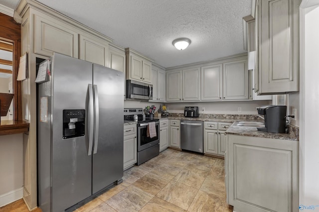 kitchen featuring stone countertops, gray cabinets, a textured ceiling, stainless steel appliances, and a sink