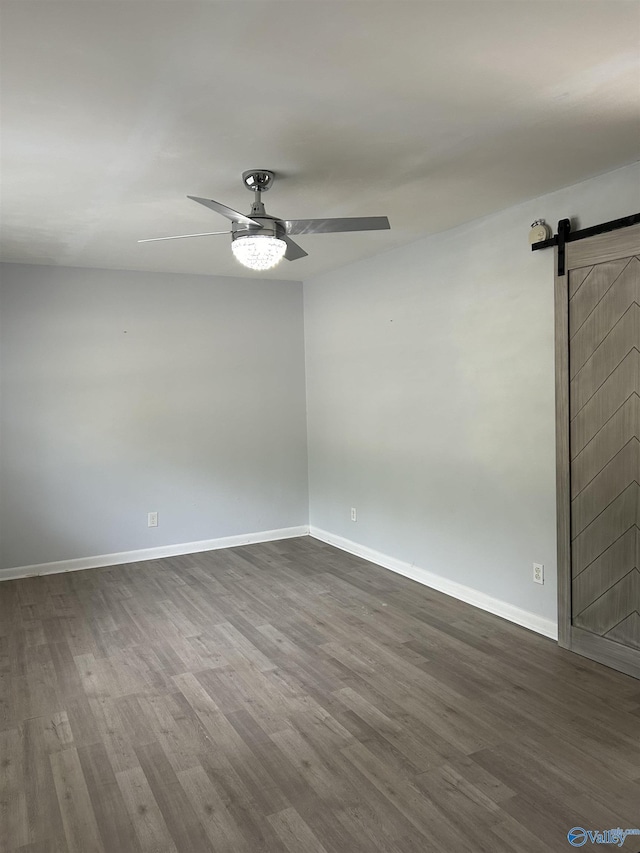 empty room featuring a barn door, ceiling fan, and hardwood / wood-style flooring