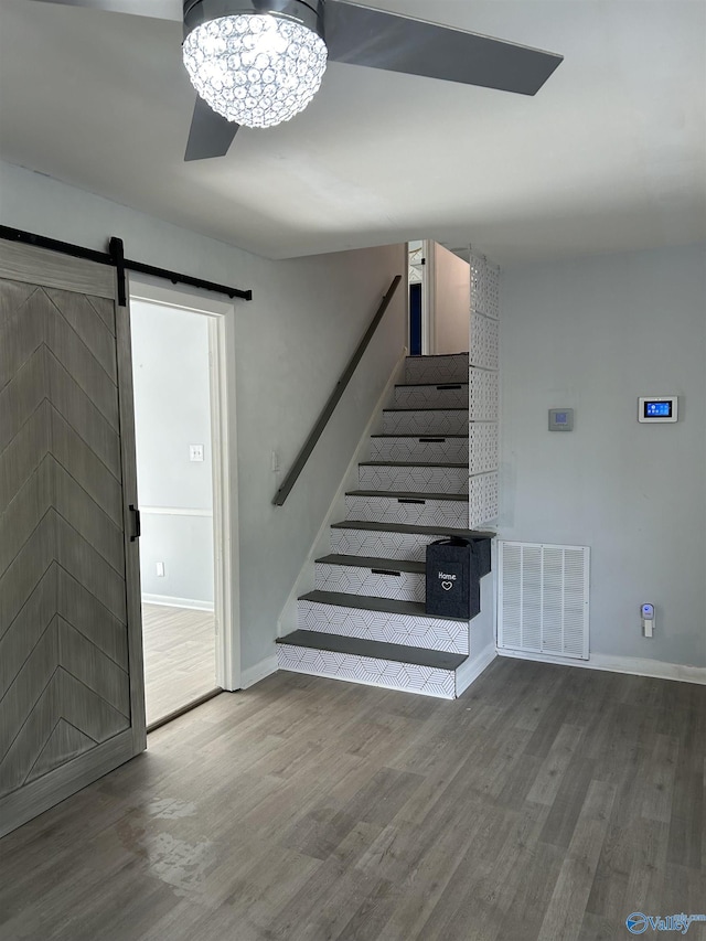 stairs featuring a barn door and wood-type flooring