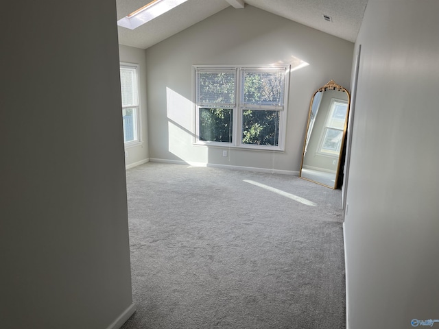 unfurnished room with carpet, vaulted ceiling with skylight, and a textured ceiling