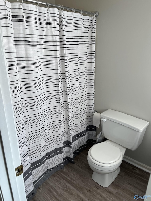 bathroom with hardwood / wood-style flooring, toilet, and a shower with shower curtain