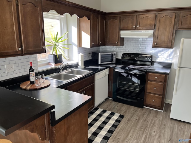 kitchen with sink, backsplash, white appliances, and light hardwood / wood-style floors