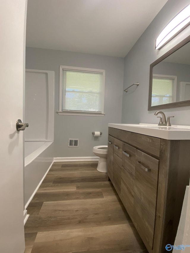 bathroom with toilet, vanity, and wood-type flooring