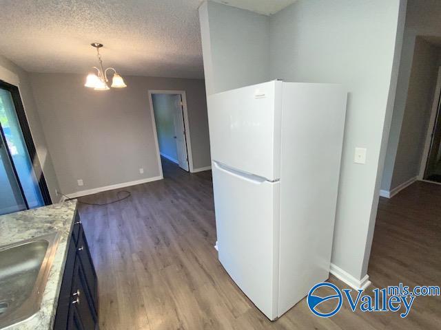2940 Hood Rd SW Unit I, Huntsville, AL 35805 - kitchen with wood finished floors, a sink, baseboards, freestanding refrigerator, and an inviting chandelier
