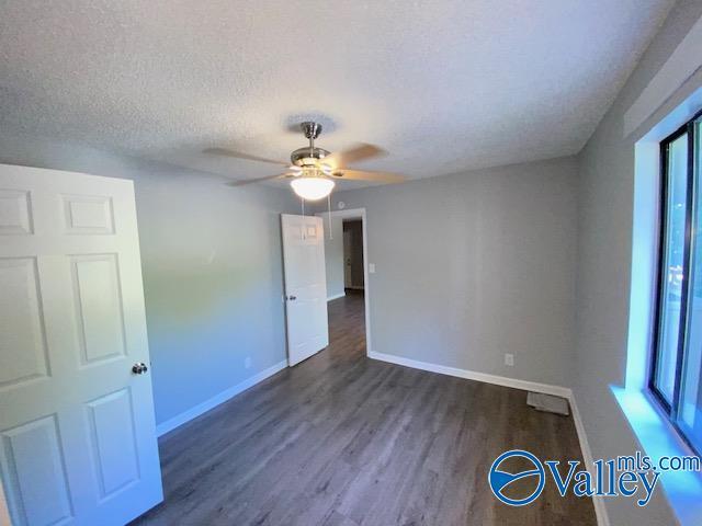 2940 Hood Rd SW Unit I, Huntsville, AL 35805 - empty room with a textured ceiling, baseboards, ceiling fan, and dark wood-type flooring