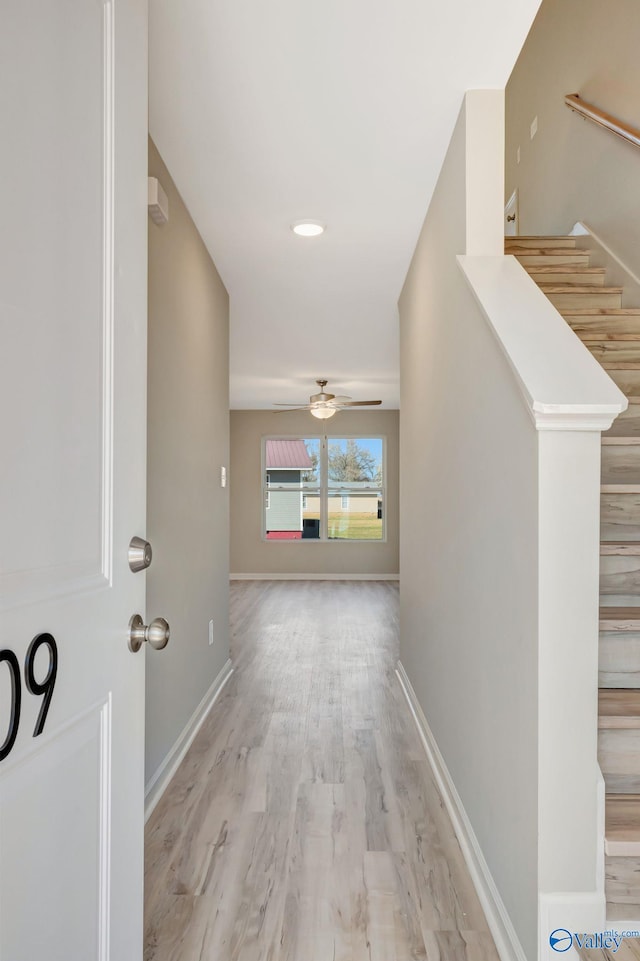 hall featuring stairway, light wood-type flooring, and baseboards