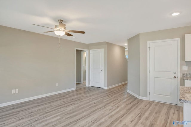 unfurnished room featuring a ceiling fan, baseboards, and light wood-type flooring