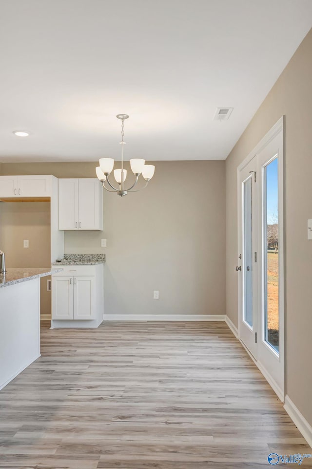 kitchen featuring baseboards, visible vents, white cabinetry, a notable chandelier, and light wood-type flooring