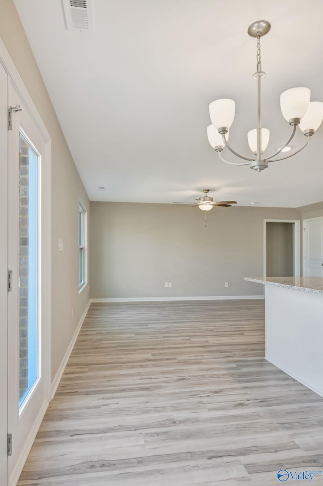 empty room featuring visible vents, light wood-style flooring, ceiling fan with notable chandelier, and baseboards