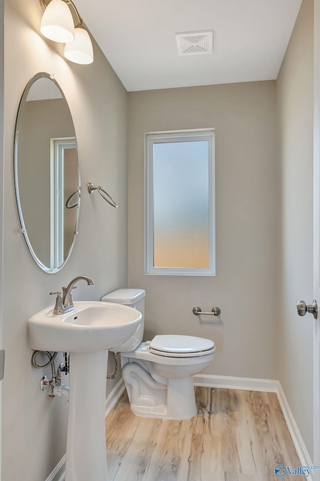 bathroom with toilet, wood finished floors, visible vents, and baseboards