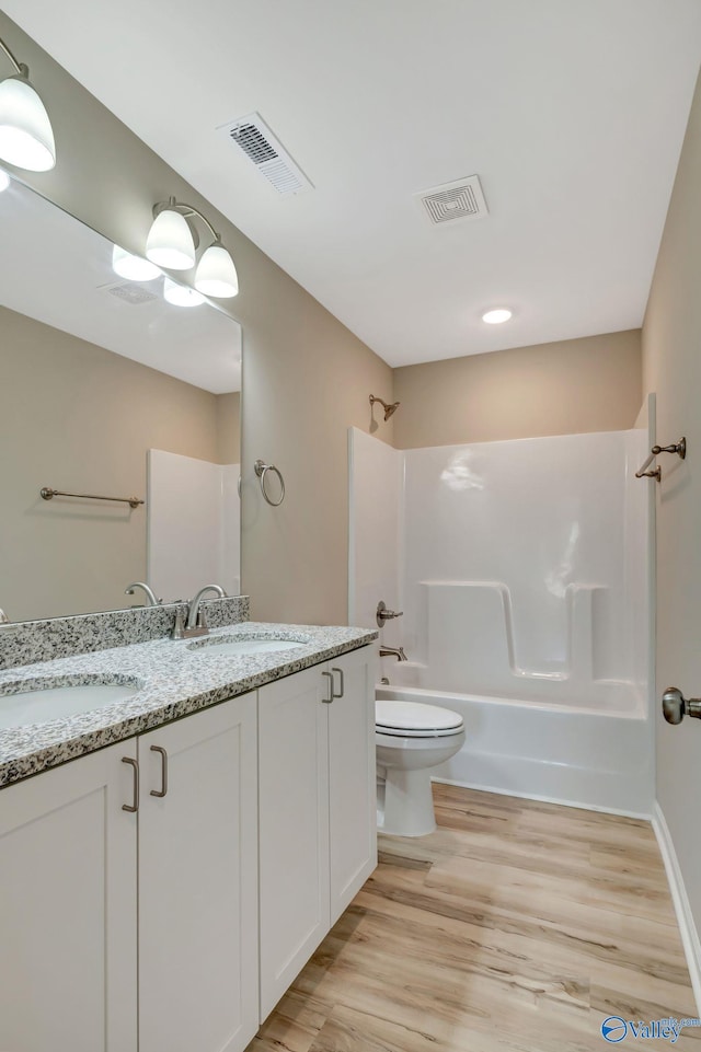 full bathroom with visible vents, wood finished floors, shower / bath combination, and a sink