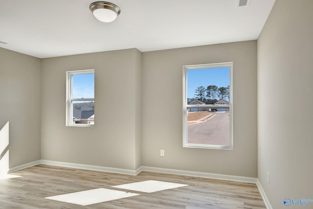 empty room featuring visible vents, baseboards, and wood finished floors