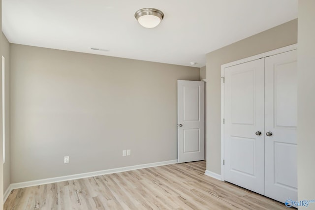 unfurnished bedroom featuring a closet, light wood-style floors, and baseboards