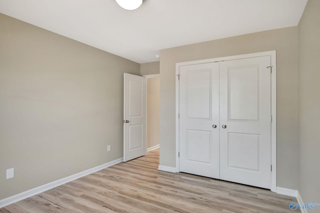 unfurnished bedroom with baseboards, a closet, and light wood-type flooring