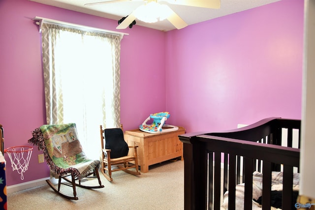 carpeted bedroom with ceiling fan and a nursery area